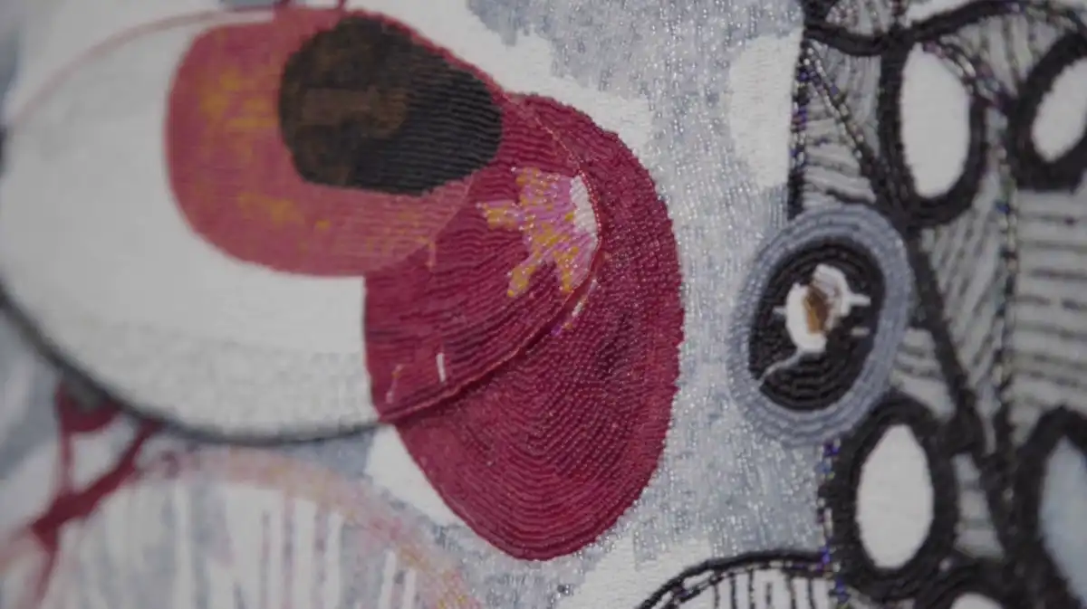 Close-up of an abstract textile artwork featuring red, black, and gray circular patterns with intricate embroidery details.