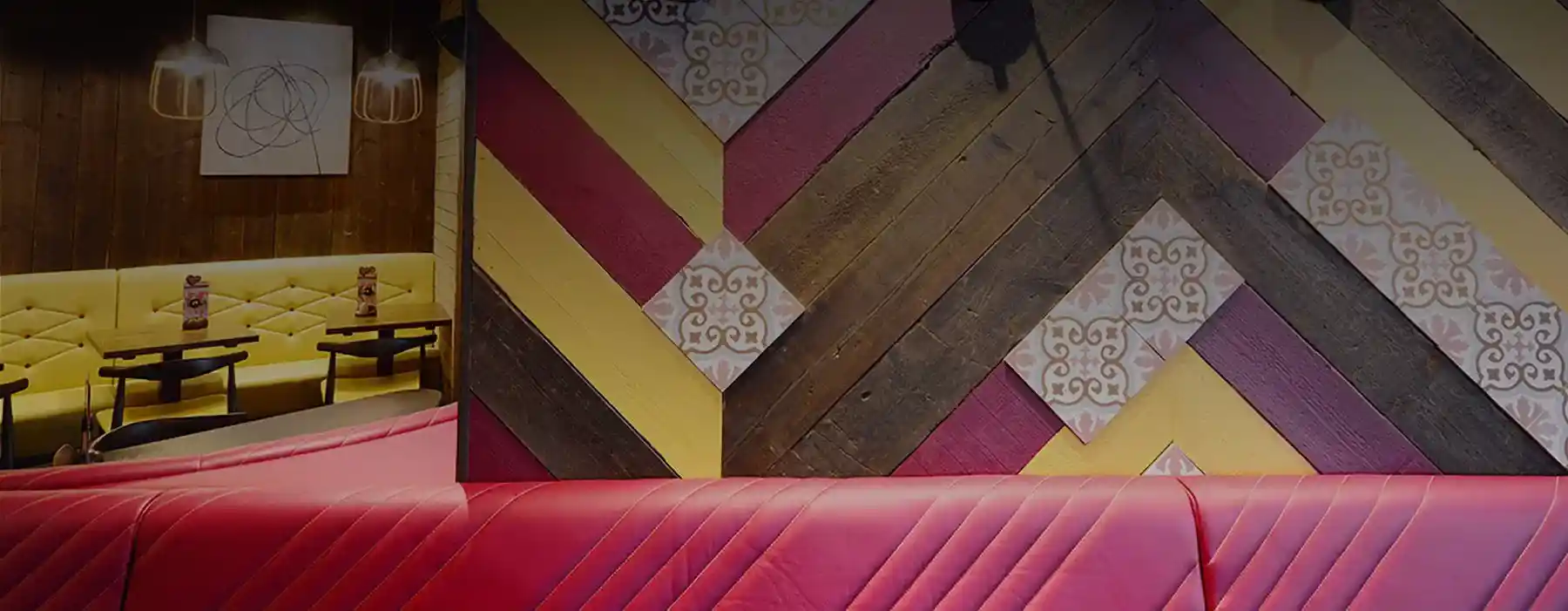 Vibrant cafe interior with red seating, geometric wall patterns, and yellow cushioned booths in the background.