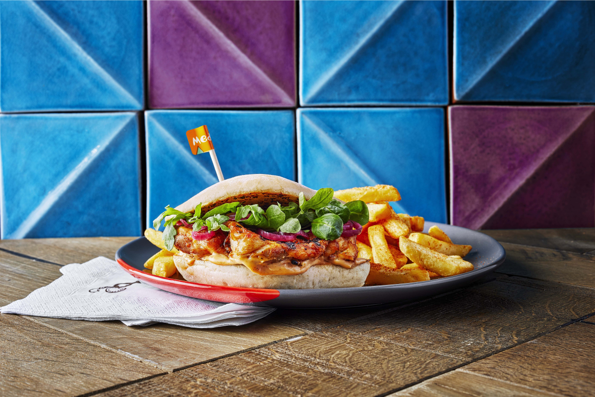 Garlic Churrasco Burger and PERi chips with a blue and purple geometric background